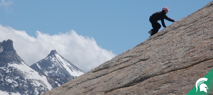 Student climbing a rocky incline
