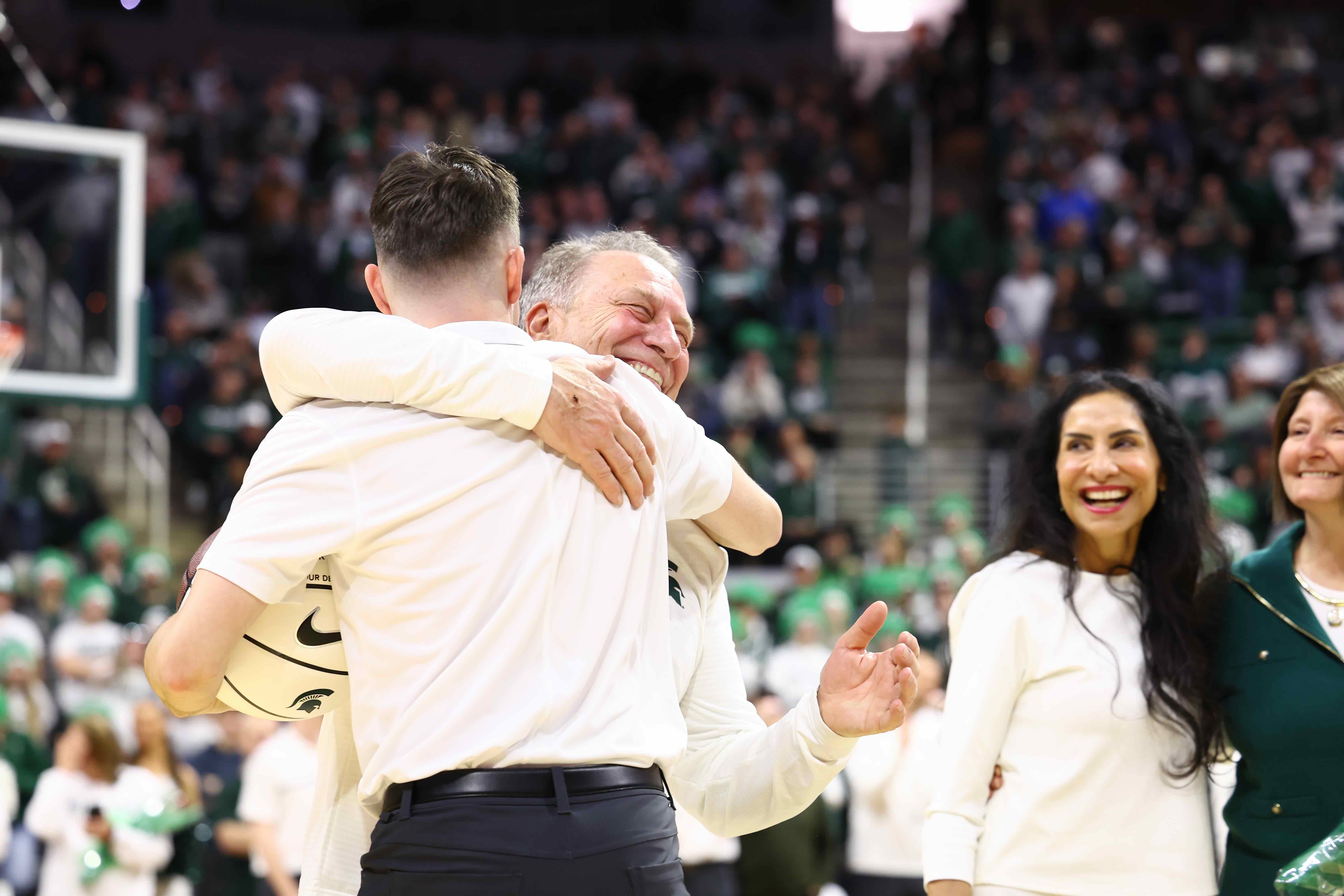 David Pruder receiving a hug from MSU Basketball Coach Tom Izzo as Lupe Izzo looks on. 