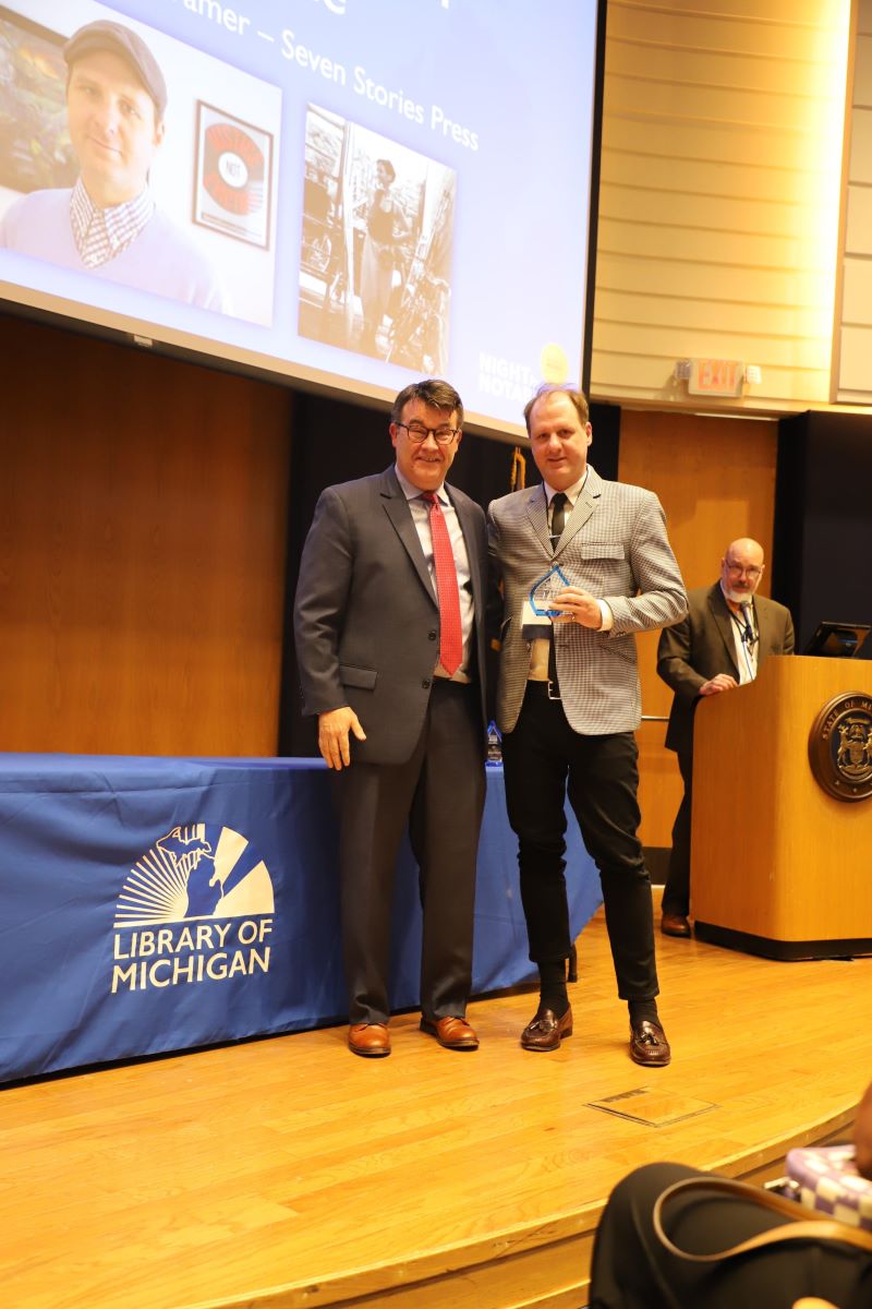 Randy Riley presents Jeffrey Wilson with 2025 Michigan Notable Book award. Photo courtesy of the Library of Michigan