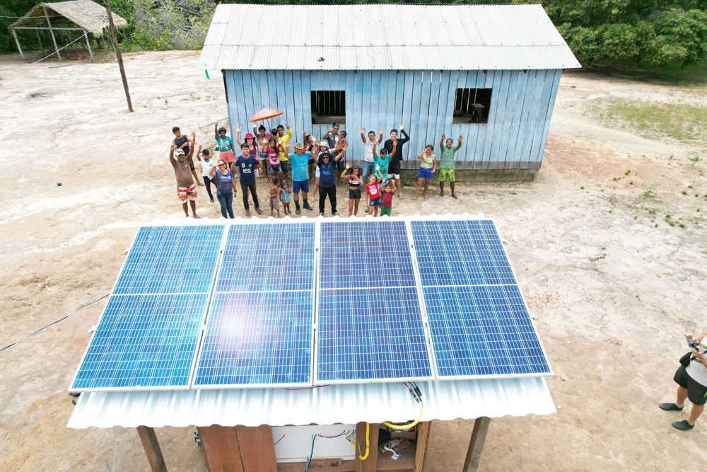 Villagers wave to drone flying above solar panels