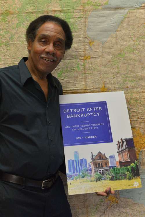 Dr. Joe T. Darden holding his new book, Detroit after Bankruptcy